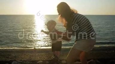 日落时分，年轻的母亲和可爱的孩子在海边散步。 孩子还很穷，我妈妈经营